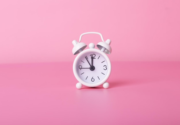 Vintage alarm clock on pink background retro modern watches high quality photo