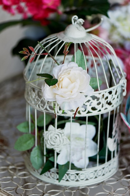 Vintage bird cage decorated with wreath made flowers tiny roses chrysanthemums and gypsophila paniculata twigs