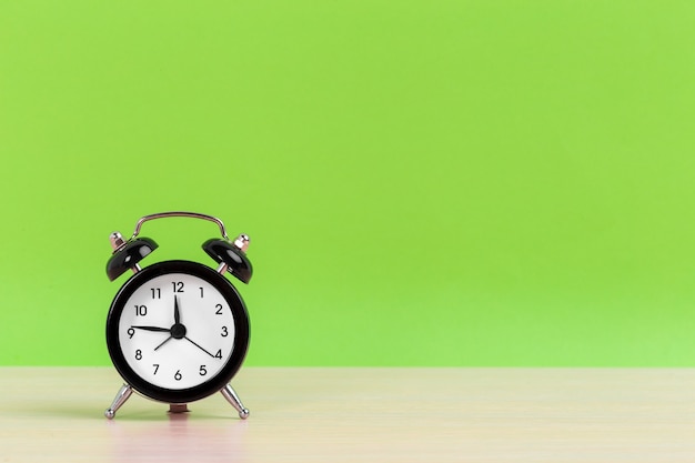 Vintage black alarm clock on bright green