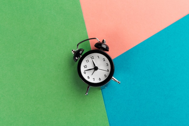 Vintage black alarm clock on a color block