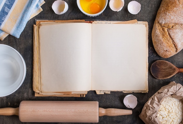 Photo vintage blank cook book with eggshell, bread, flour, rolling pin