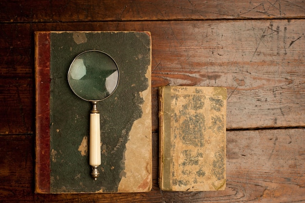 vintage books with optical magnifying glass on old wooden table