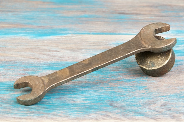 Vintage bronze wrench on shabby blue wooden background. Copy space for text.