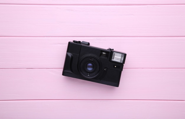 Vintage camera on pink wooden background. 