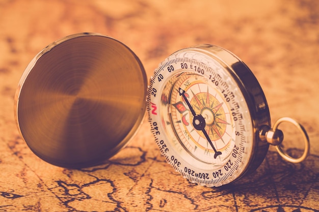 vintage compass on old global map close up.