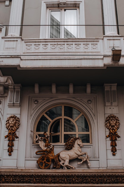 Vintage facade of an european ancient building with a golden statue of a horse. Details of historical architecture