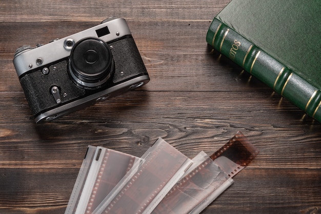 Vintage film camera film and photo album on a dark wooden table top view old retro technology