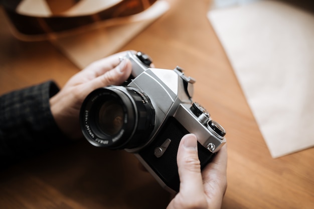 Vintage film camera in the man hands on a wooden space