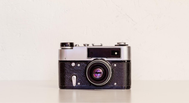 Vintage film camera on a table against a white wall close-up, front view