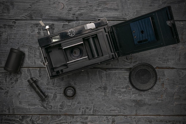 Photo vintage film camera on wooden background with film roll and lens cap