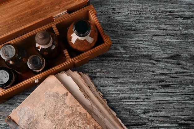 Vintage glass bottles in box with old book on wooden background closeup