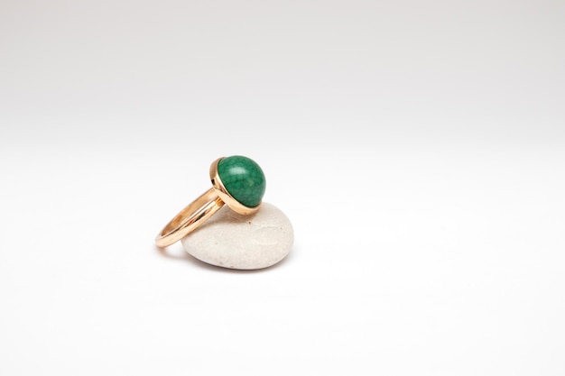 Vintage gold ring with green stone on gray pebbles.