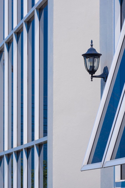 vintage lantern with geometric pattern of glass window on modern building wall in vertical frame