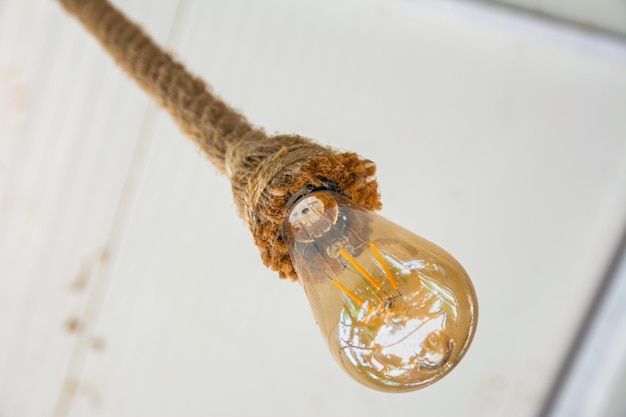 A vintage light bulb hangs from the ceiling on a rope