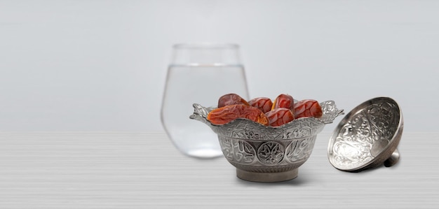 Vintage metal bowl full of pitted date fruits on wooden table.  Traditional iftar food. Symbolizing