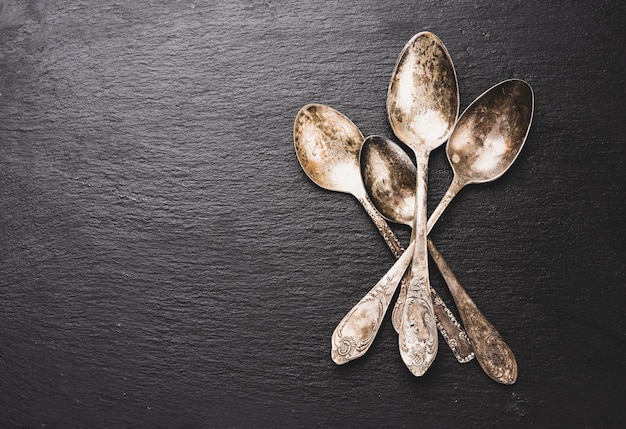 Vintage metal empty spoons on black surface