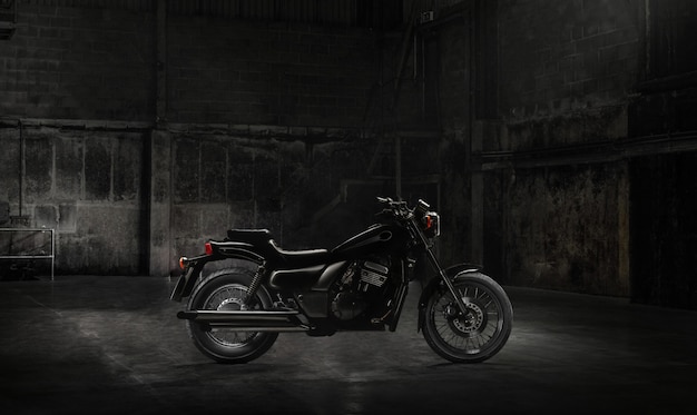 Vintage motorcycle standing in a dark building in the rays of sunlight. Side view