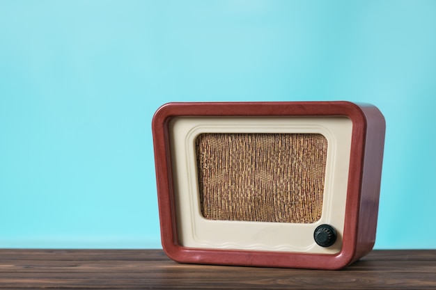 Vintage radio on a wooden table on a blue background. Radio engineering of the past time. Retro design.