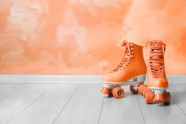 Vintage roller skates on floor near orange wall Space for text