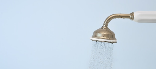 Vintage Shower head with flowing Water on blue background. Copy space