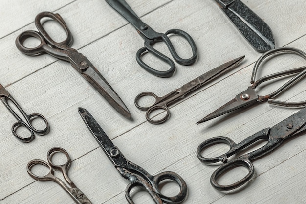 Vintage steel scissors on wooden table background. Old-fashioned instruments for florist, barber, seamstress. History, professional collection of equipment, beauty of workplace. Vintage, retro style.