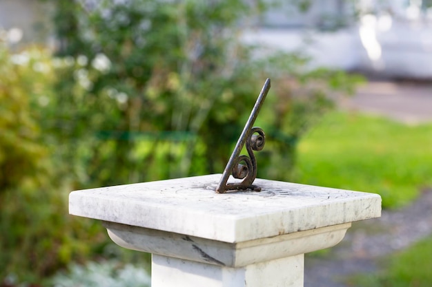 A vintage sundial with green patina throws a long shadow tracking the motion of the sun while telling the time