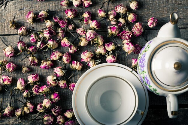 Photo vintage teapot and cup with blooming tea flowers on wooden surface