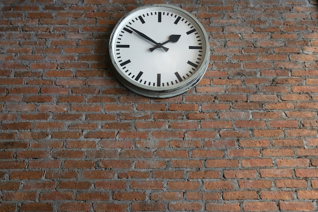 Vintage white clock on the old brick wall background