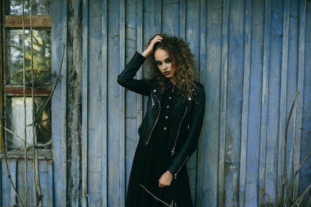 Vintage woman as witch, posing against the backdrop of an abandoned place on the eve of Halloween