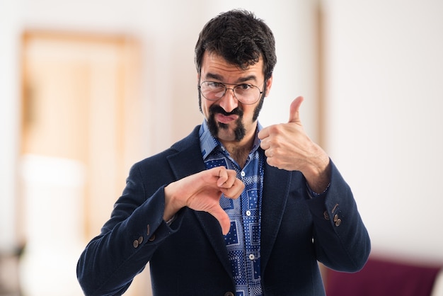 Vintage young man making good-bad sign  on unfocused background