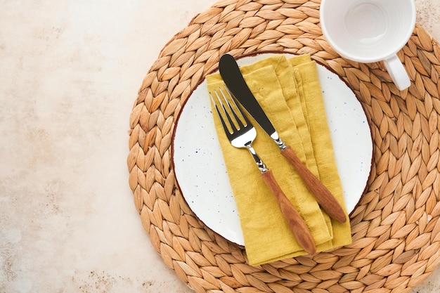 Vintage zero waste silverware Rustic vintage set of white plate wooden spoon and fork on napkin for dishes from water hyacinth on light gray concrete background Empty dishes Top view Mock up