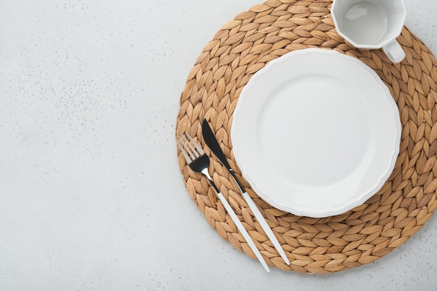 Vintage zero waste silverware Rustic vintage set of white plate wooden spoon and fork on napkin for dishes from water hyacinth on light gray concrete background Empty dishes Top view Mock up