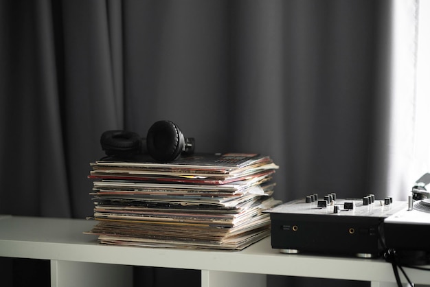 A vinyl music records stack on the shelf with headphones on top