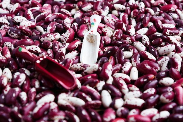 Violet with dots beans and two wooden spoons background