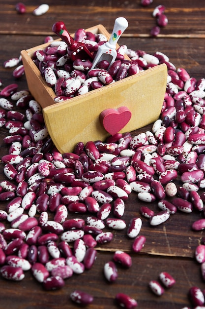 Violet with dots beans in wooden box with heart and two spoons.