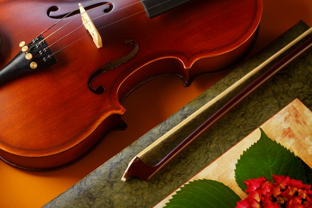 Violin and bow with book on yellow background