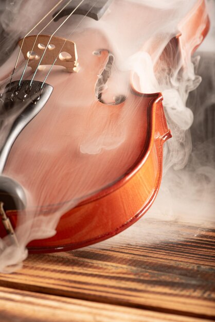 Violin with smoke beautiful violin covered with a thin smoke screen on rustic wood and black background selective focus