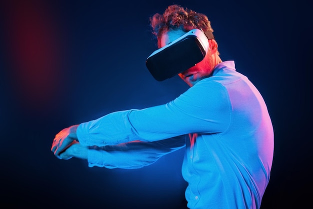 Virtual glasses gaming experience Neon lighting Young european man is in the dark studio