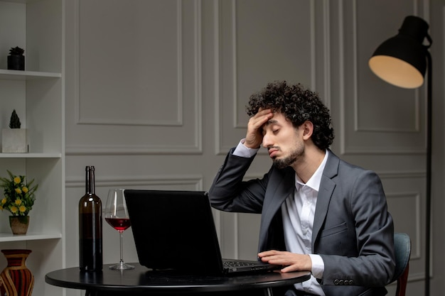 Virtual love handsome cute guy in suit with wine on a distance computer date holding forehead