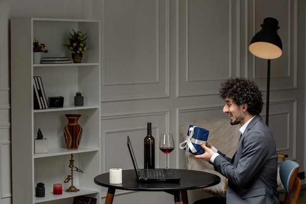 Virtual love handsome cute guy in suit with wine on a distance computer date holding present