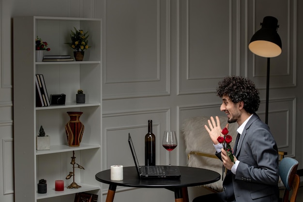 Virtual love handsome cute guy in suit with wine on a distance computer date saying hello