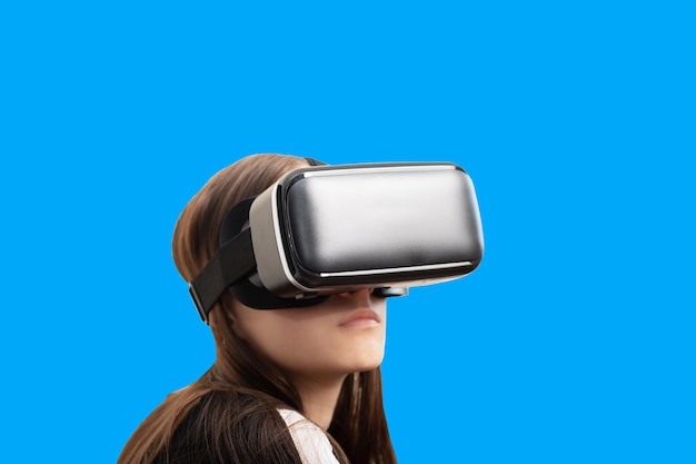 Virtual reality and modern technologies Girl gamer in VR glasses isolated on a blue background