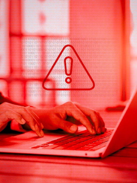 Photo virus alert red triangle system hacked error sign malware attention danger symbol warning showing on binary code while business person working with laptop computer red tone vertical style