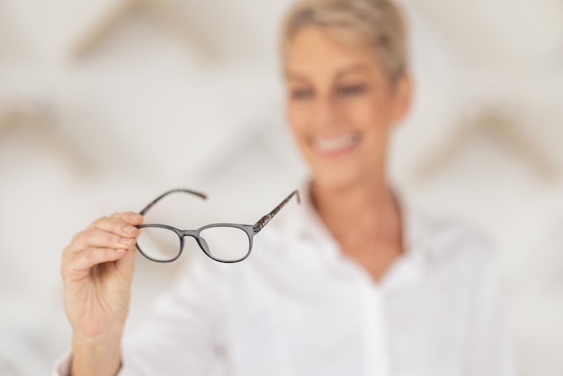 Vision blur and woman holding glasses in an optometry store buying prescription lenses Retail optometrist and senior lady trying spectacles in optician optical or eyewear shop for eye care