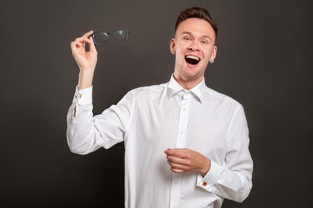 Vision correction Laser eye surgery Excited hipster guy happy to take off eyeglasses isolated on black Amazed man enjoying perfect eyesight New perspective view