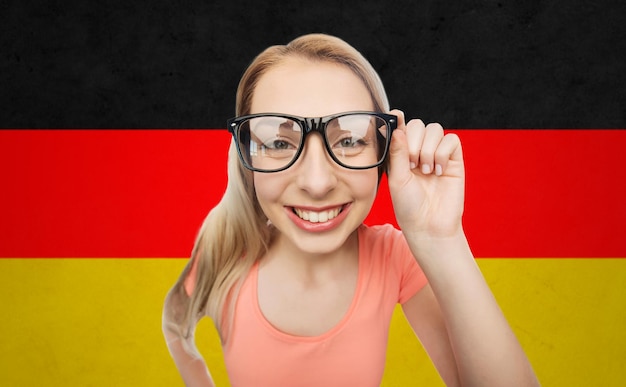 vision, education, national and people concept - happy smiling young woman or teenage girl eyeglasses over german flag background