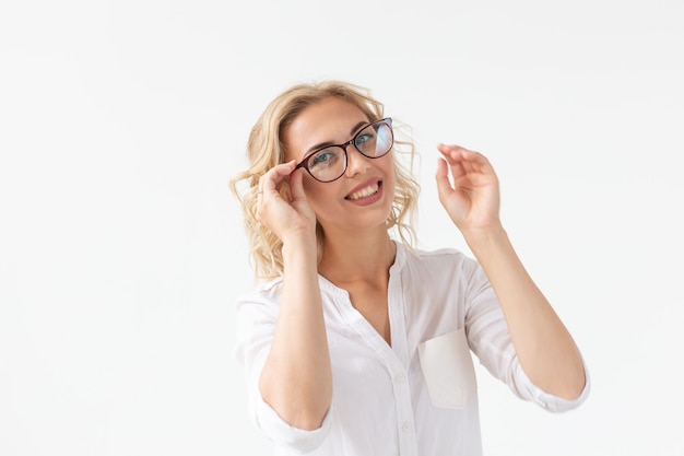 Vision optics and beauty  young blond woman putting on a pair of glasses on white wall