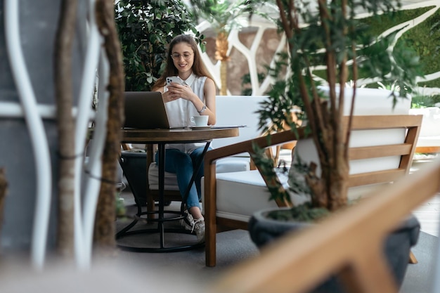 Visitor of a cozy internet cafe reading a message on her smartphone