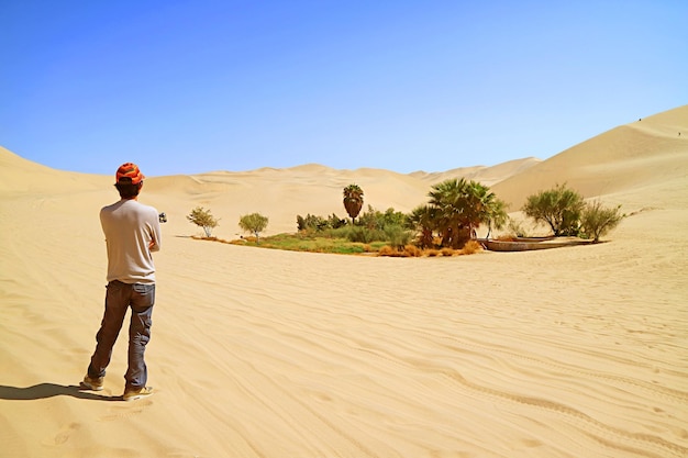 Visitor looking at the small oasis on the vast sand dunes of Huacachina desert in Ica region Peru