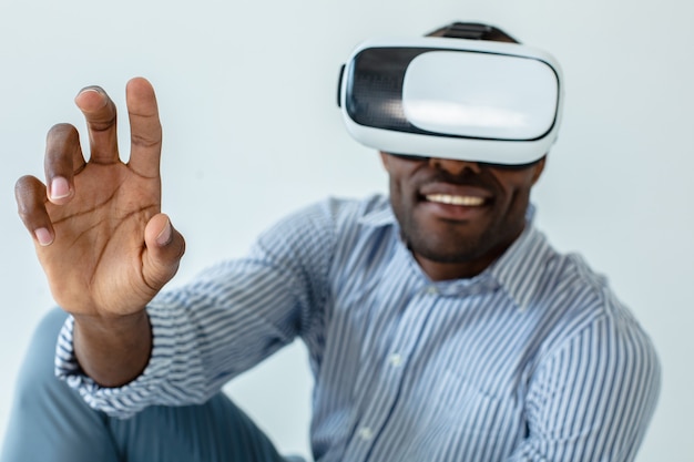 Visualize your dreams. Positive handsome afro american man wearing VR glasses while expressing joy